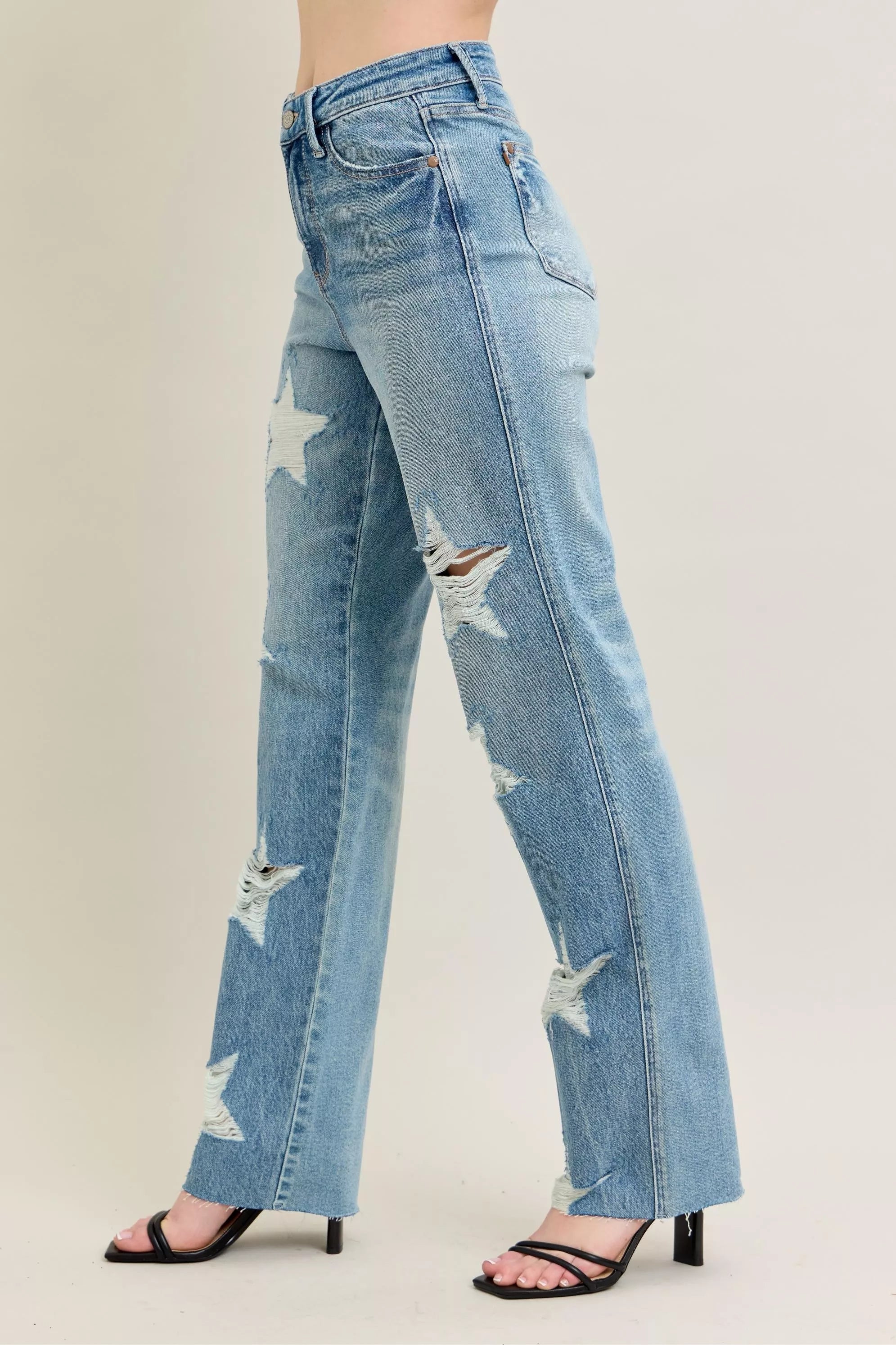 NEWYORKLISTED STYLE COLLECTION: Light blue distressed jeans worn by a person on a plain background