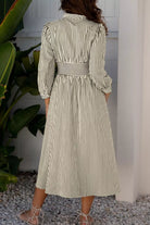 NEWYORKLISTED STYLE COLLECTION: Woman wearing a striped dress standing in a room with plants.