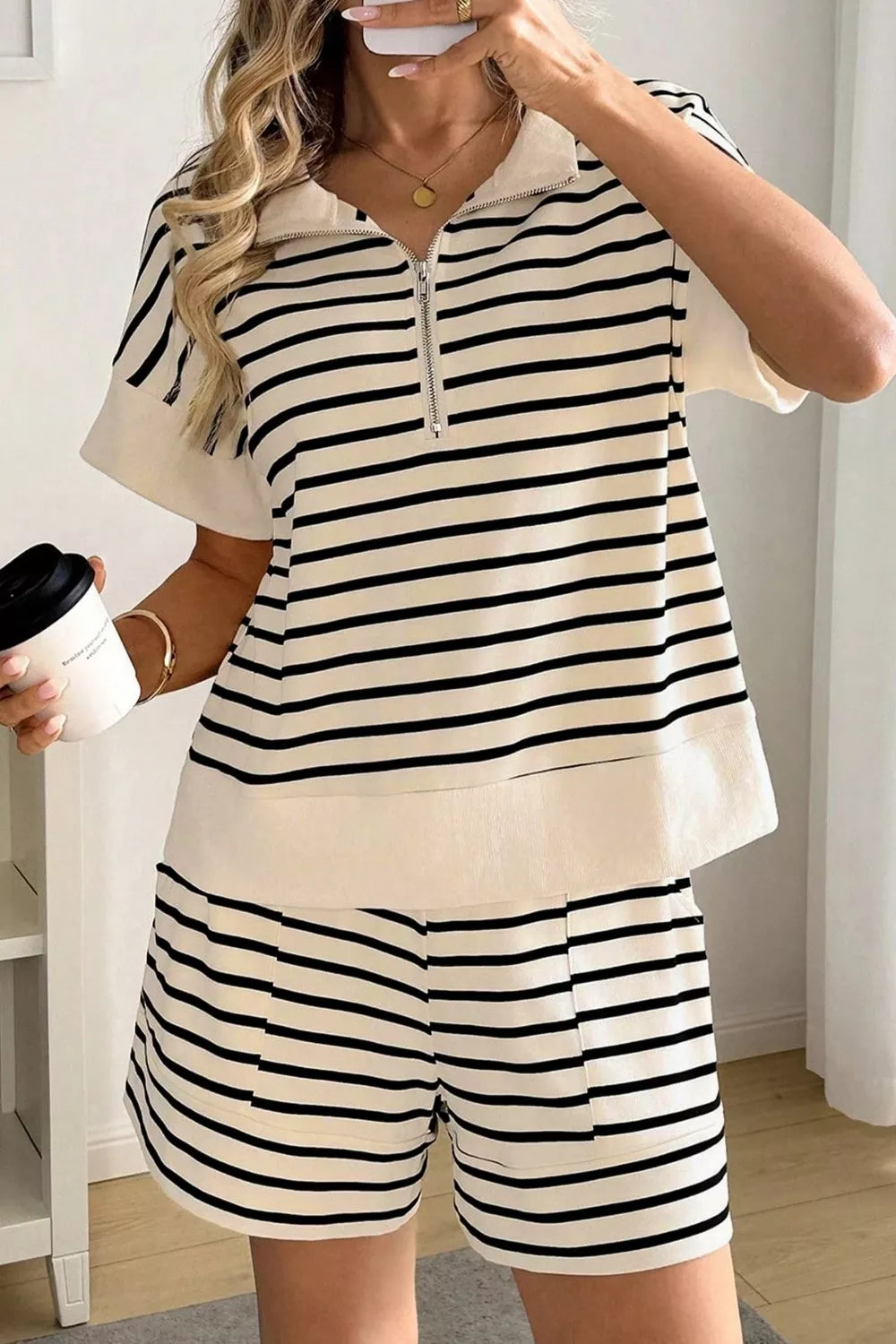 NEWYORKLISTED STYLE COLLECTION: Person wearing a black and white striped outfit holding a coffee cup.