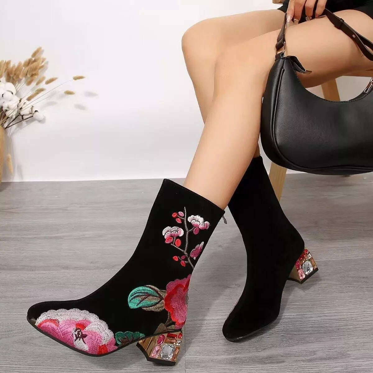 NEWYORKLISTED Shoe Collection: Black embroidered socks with floral designs worn by a person sitting on a chair.