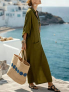 NEWYORKLISTED STYLE COLLECTION: Woman in a green dress holding a straw bag with blue accents, standing by the ocean.