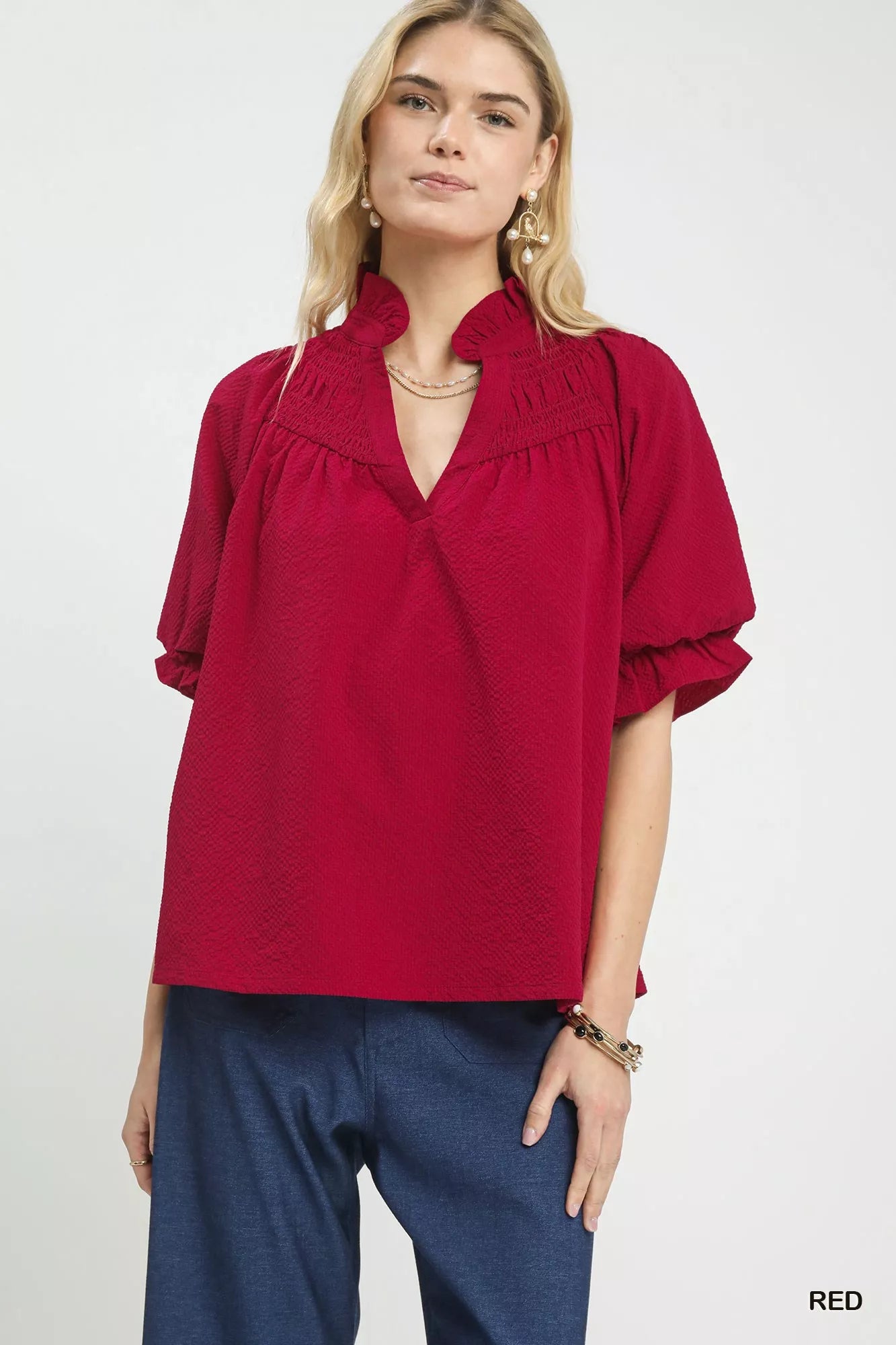 NEWYORKLISTED Style Collection: Woman wearing a red blouse with ruffled collar on a white background