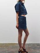 NEWYORKLISTED STYLE COLLECTION: Person wearing a denim outfit with a skirt and jacket against a plain background