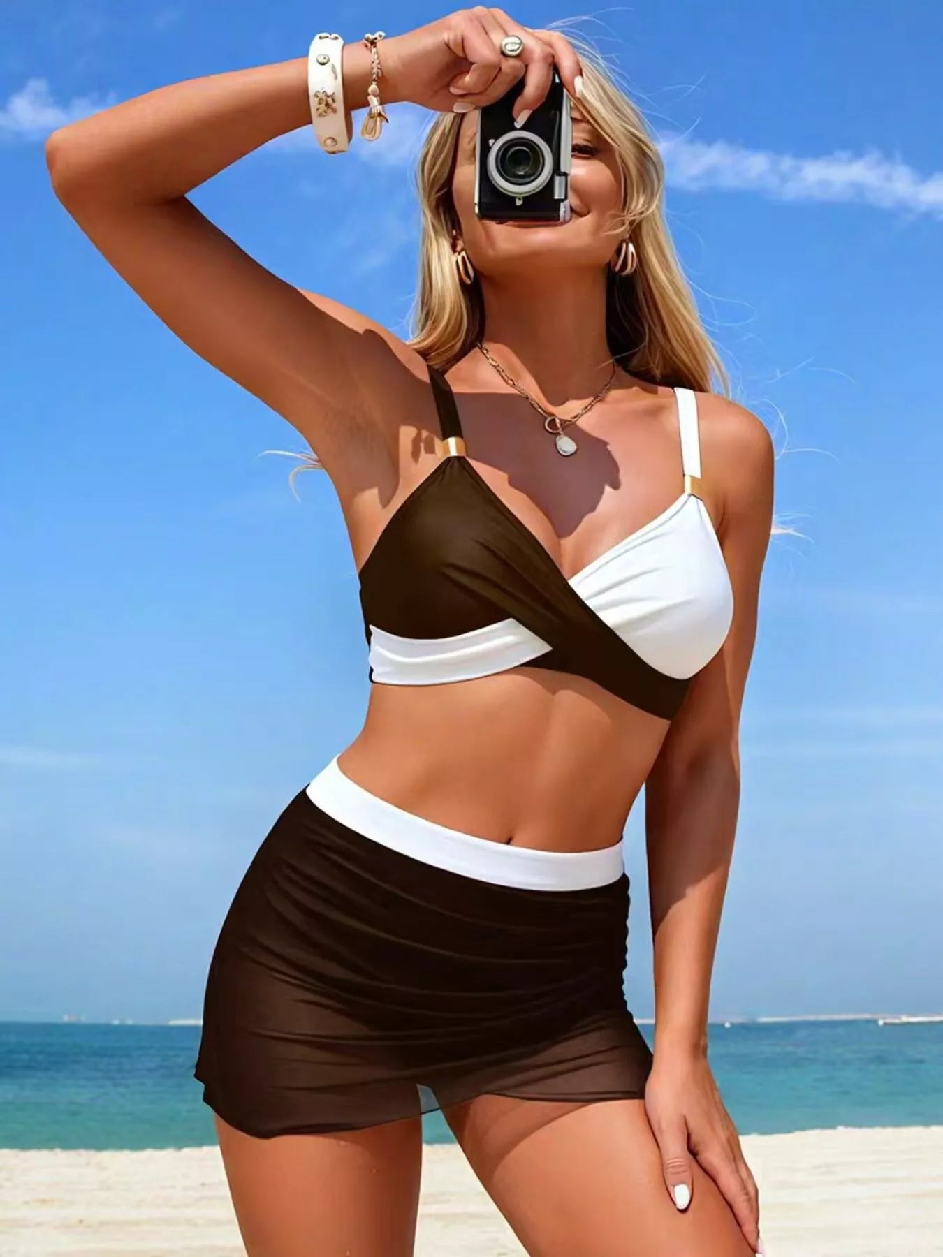 NEWYORKLISTED EDEN COLLECTION: Woman in a brown and white bikini taking a selfie on a beach.