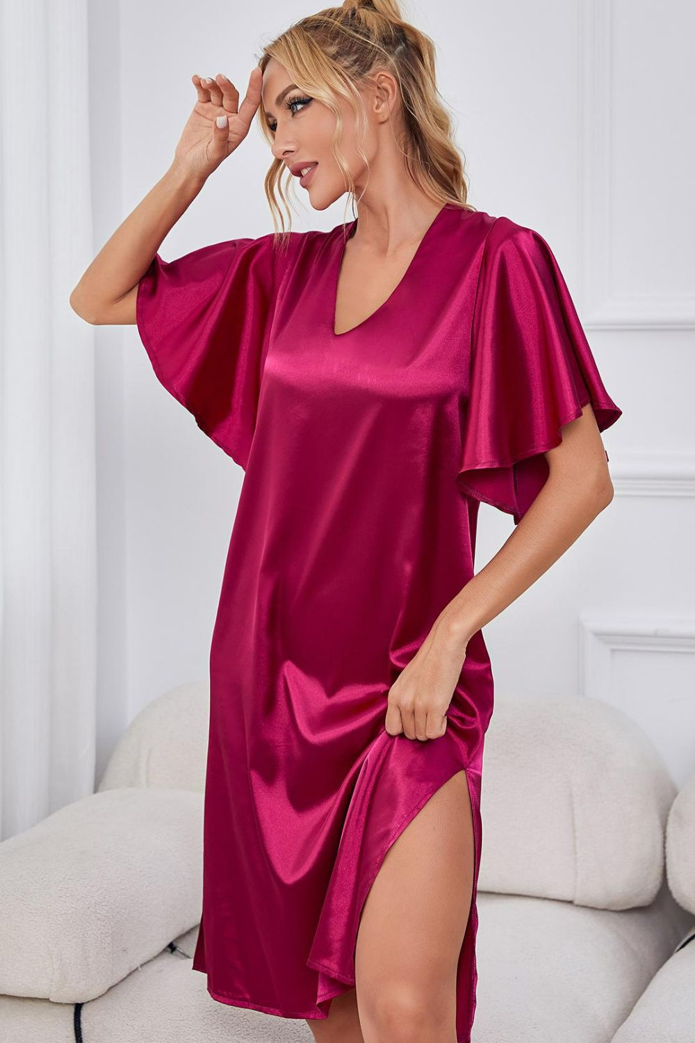 NEWYORKLISTED Intimate Apparel: Woman wearing a pink satin nightgown sitting on a white couch.