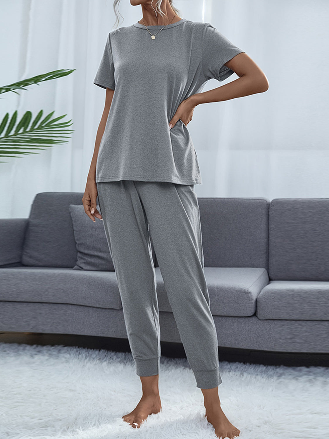 NEWYORKLISTED Intimate Apparel: Person wearing a gray pajama set in a living room setting.