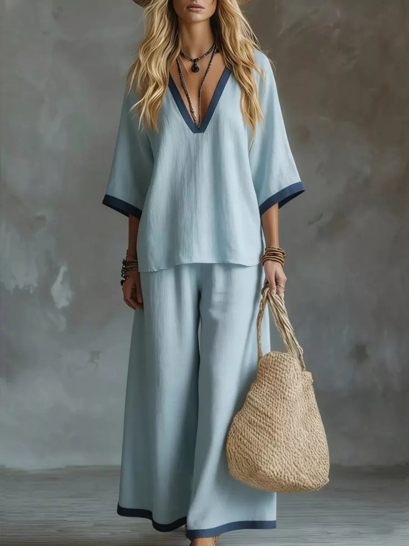 NEWYORKLISTED STYLE COLLECTION: Woman in light blue outfit holding a woven bag against a neutral background