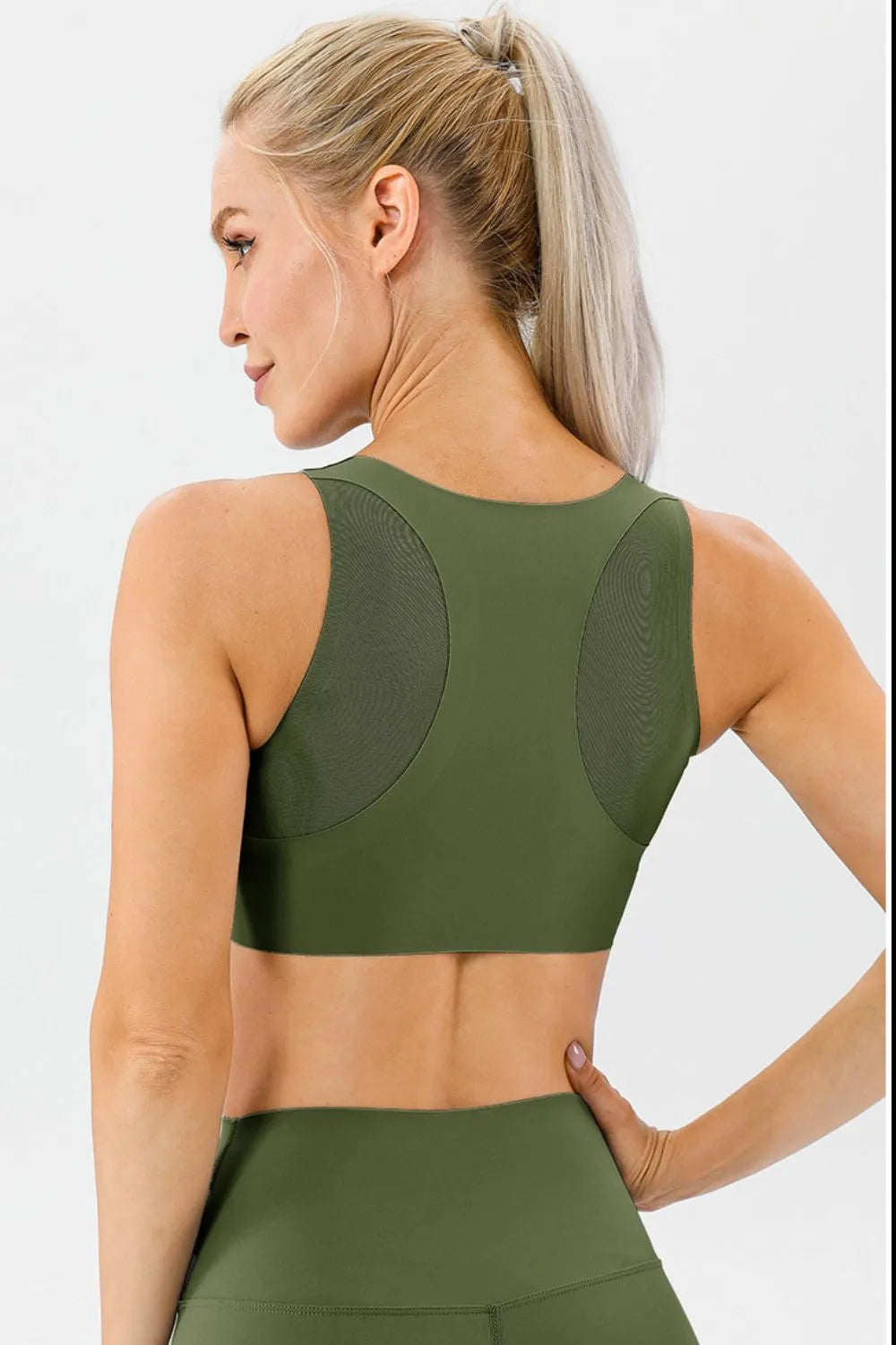 NEWYORKLISTED ACTIVEWEAR COLLECTION: Woman wearing a green sports bra and leggings on a white background