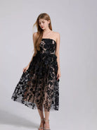 NEWYORKLISTED STYLE COLLECTION: Woman wearing a black floral dress on a gray background