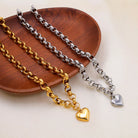 NYLD Glamour Collection by NEWYORKLISTED: Three gold and silver chain necklaces with heart pendants on a wooden plate.