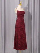 NEWYORKLISTED STYLE COLLECTION: Burgundy evening gown on a mannequin against a gray curtain background