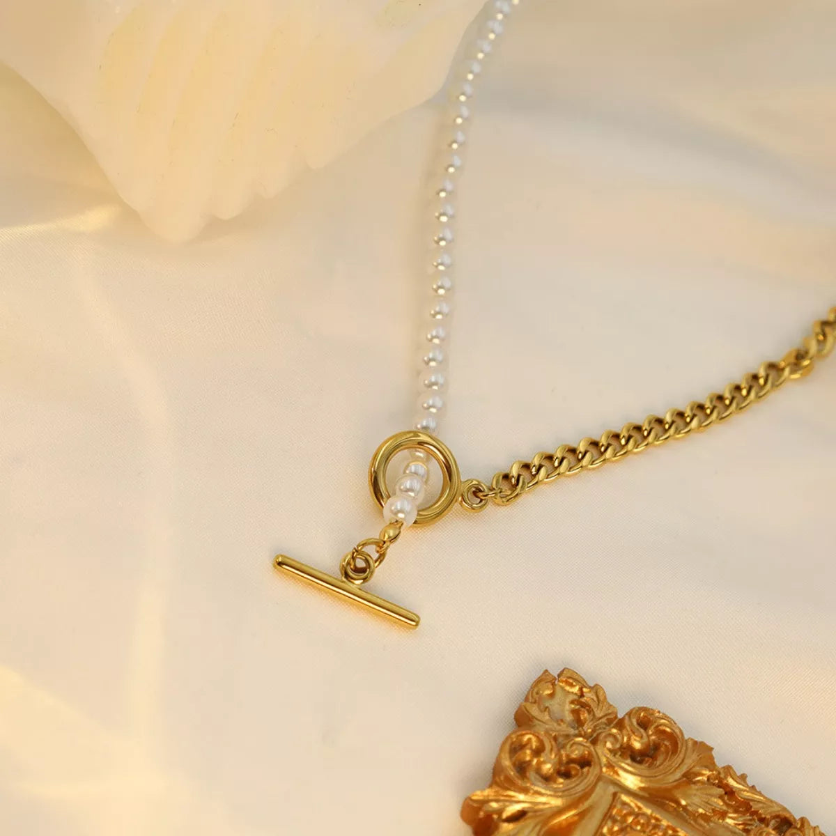 NYLD Glamour Collection by NEWYORKLISTED: Gold necklace with a clasp on a soft beige background