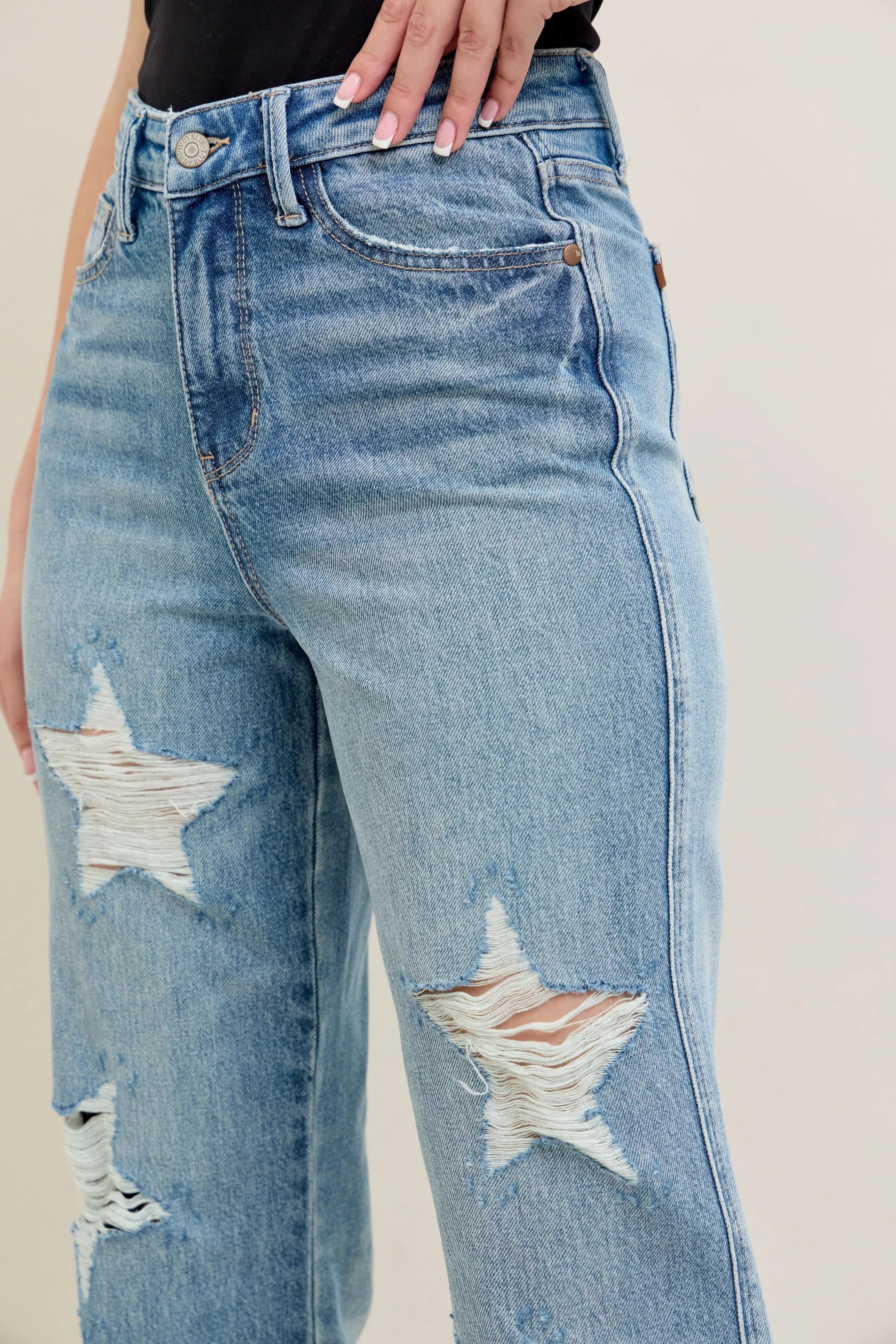 NEWYORKLISTED STYLE COLLECTION: Distressed blue jeans with star designs on a neutral background