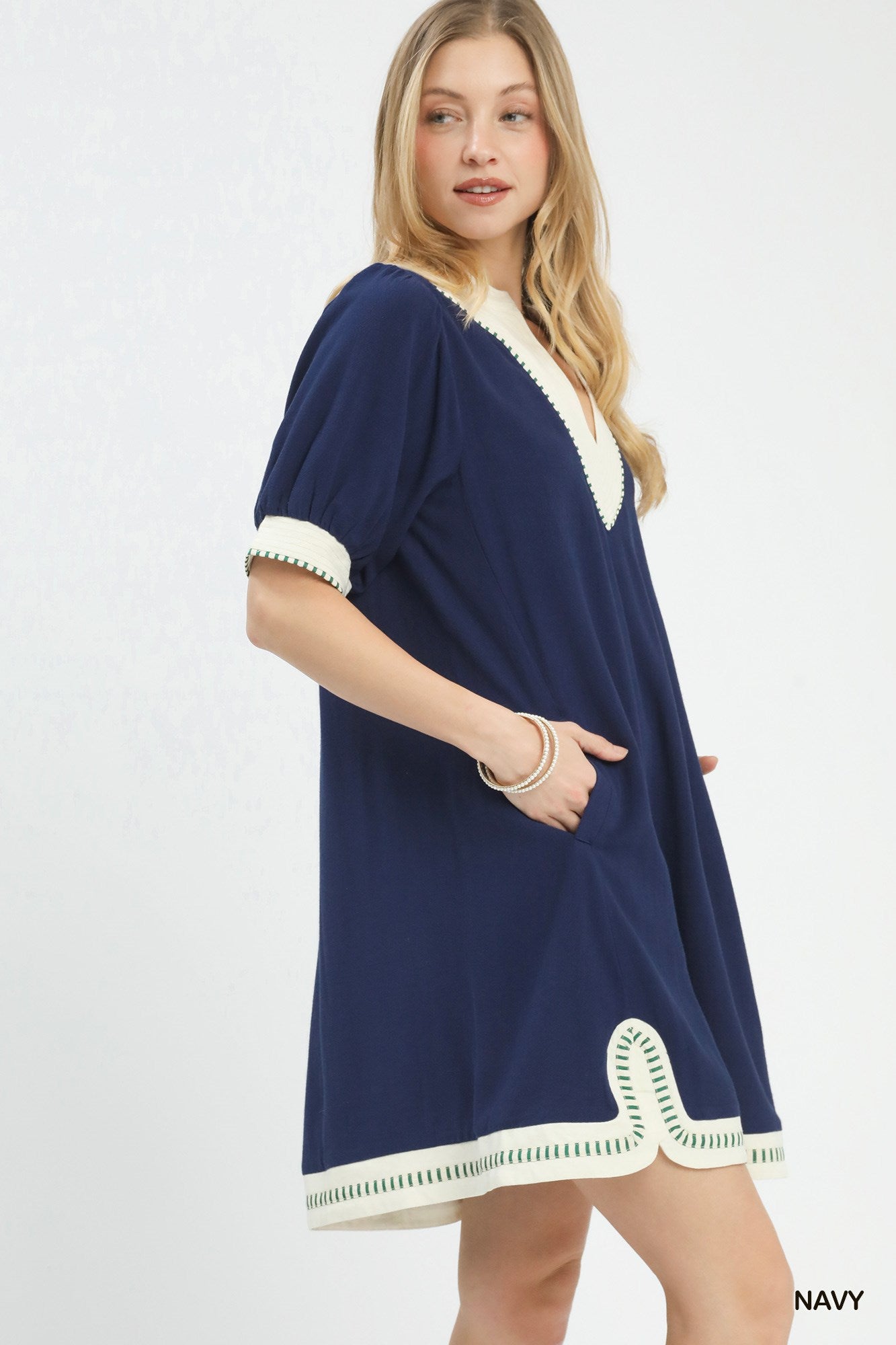 NEWYORKLISTED STYLE COLLECTION: Woman wearing a navy dress with white trim on a light gray background
