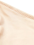 NEWYORKLISTED Intimate Apparel: Close-up of beige fabric with a focus on stitching detail