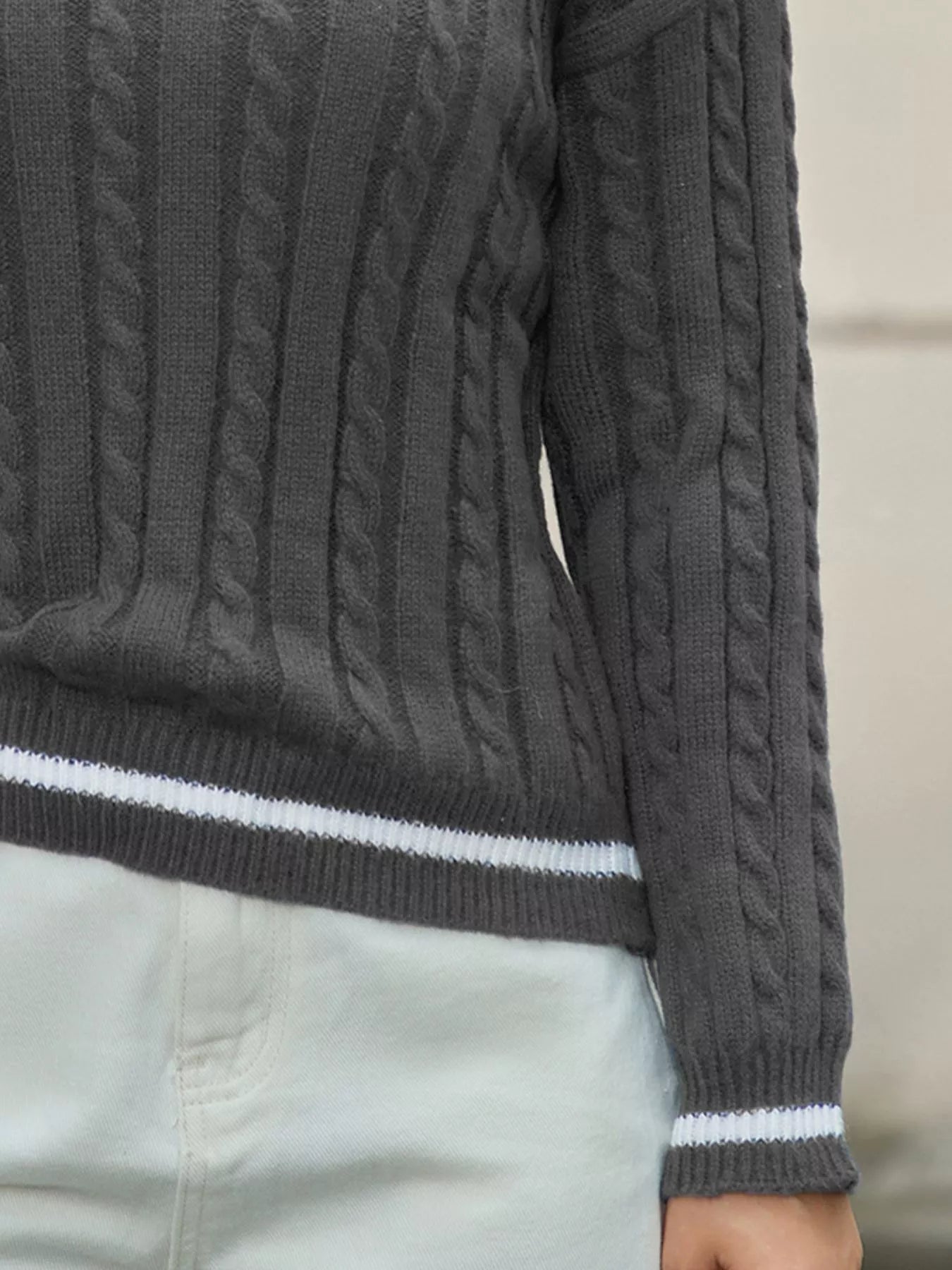 NEWYORKLISTED STYLE COLLECTION: Dark gray cable knit sweater with white trim on a neutral background