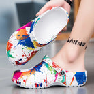 NEWYORKLISTED STYLE COLLECTION: Colorful splatter-patterned clogs being worn with a blurred background