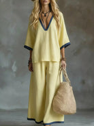 NEWYORKLISTED STYLE COLLECTION: Woman in a yellow outfit holding a woven bag against a textured gray background