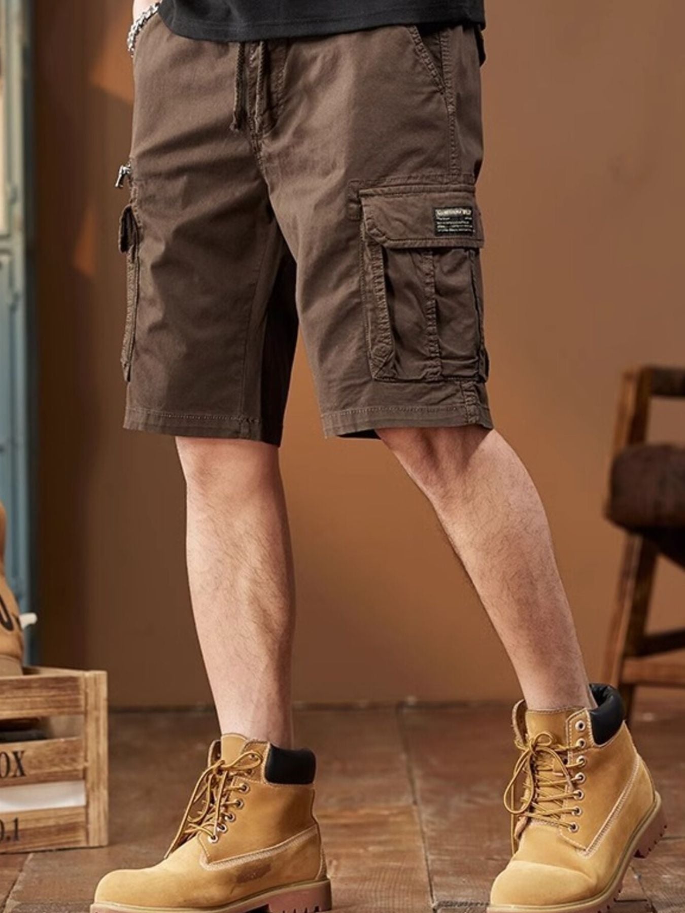 NEWYORKLISTED ATLAS MEN's COLLECTION: Person wearing brown cargo shorts and yellow boots indoors.