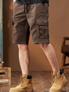 NEWYORKLISTED ATLAS MEN's COLLECTION: Person wearing brown cargo shorts and yellow boots indoors.