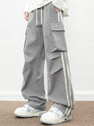 NEWYORKLISTED ATLAS MEN's COLLECTION: Person wearing gray cargo pants with white stripes and white sneakers on a plain background