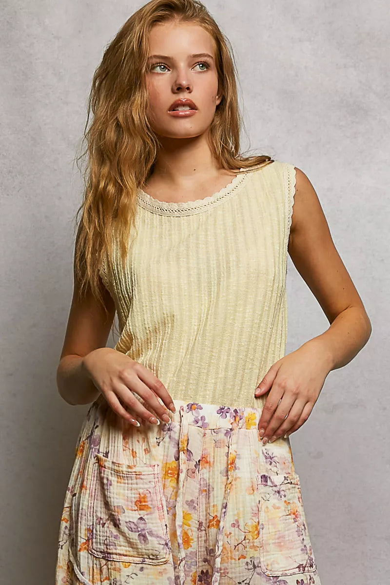NEWYORKLISTED STYLE COLLECTION: Woman wearing a light yellow sleeveless top and a floral skirt against a gray background