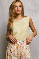 NEWYORKLISTED STYLE COLLECTION: Woman wearing a light yellow sleeveless top and a floral skirt against a gray background