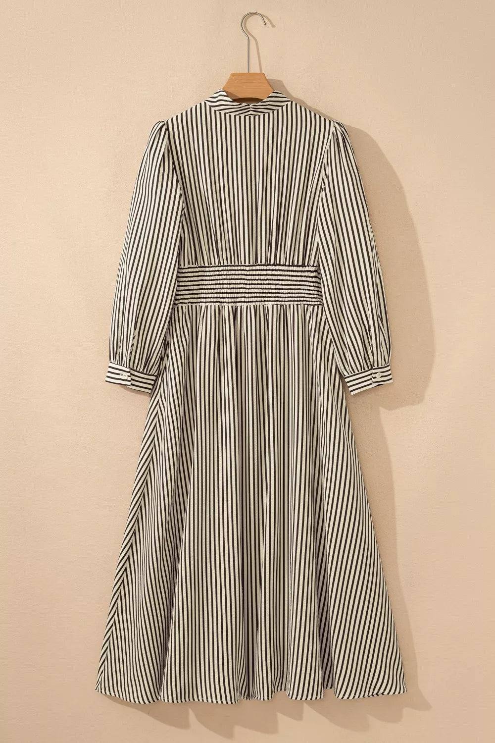 NEWYORKLISTED STYLE COLLECTION: Striped dress on a hanger against a beige background