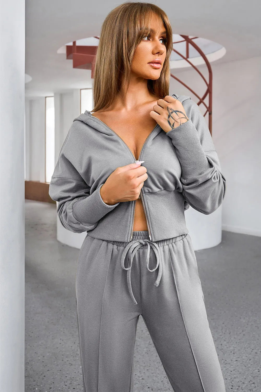NEWYORKLISTED ACTIVEWEAR COLLECTION: Woman wearing a gray tracksuit in an indoor setting