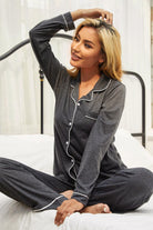 NEWYORKLISTED Intimate Apparel: Woman wearing a gray pajama set sitting on a bed.