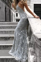 Woman in a silver sequin dress standing on stone steps.