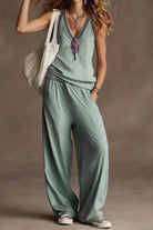 NEWYORKLISTED STYLE COLLECTION: Woman wearing a green sleeveless top and wide-leg pants against a brown background