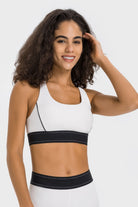 NEWYORKLISTED ACTIVEWEAR COLLECTION: Woman wearing a white sports bra with black waistband on a white background