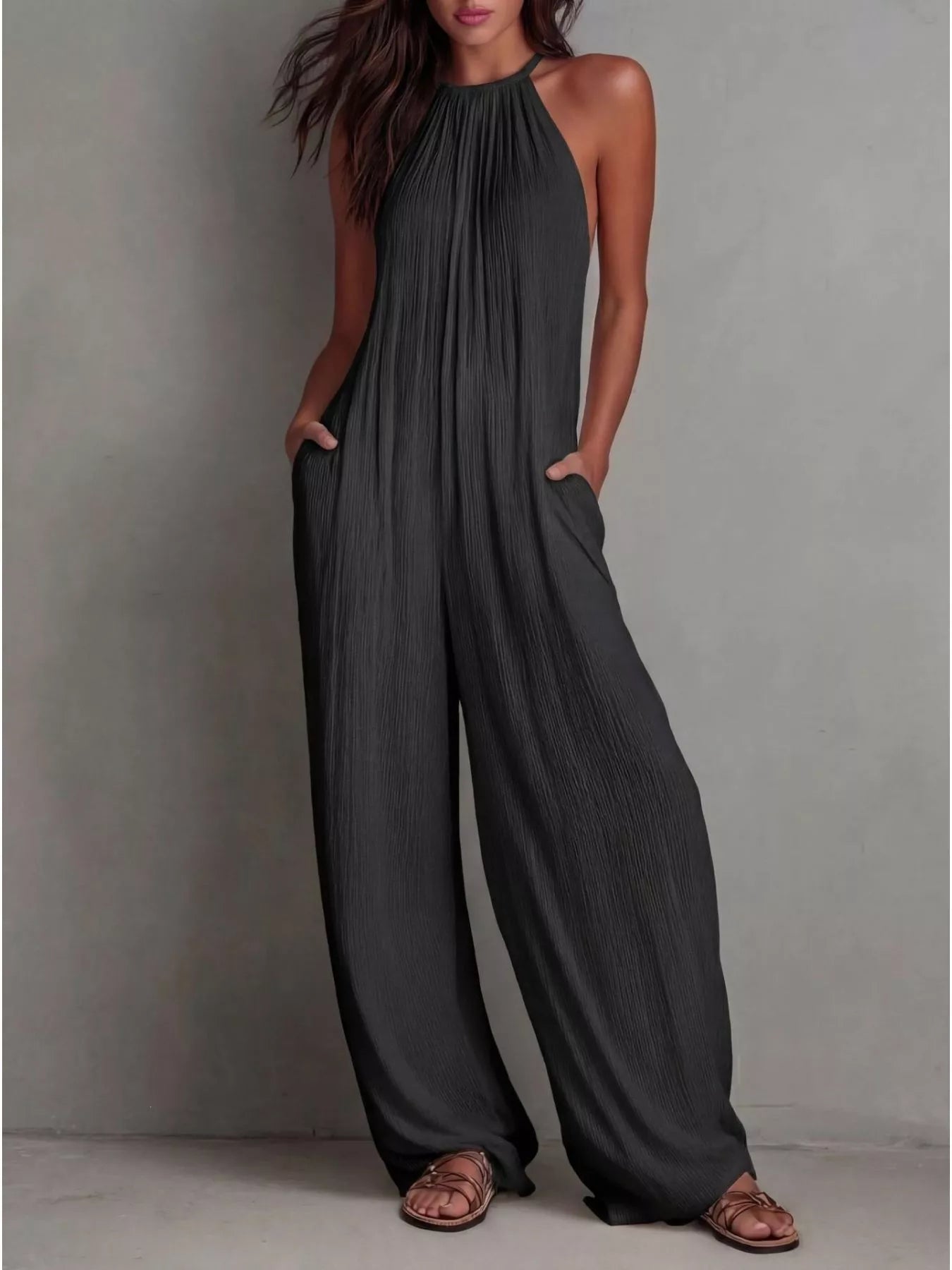 NEWYORKLISTED STYLE COLLECTION: Woman wearing a dark gray jumpsuit against a plain background