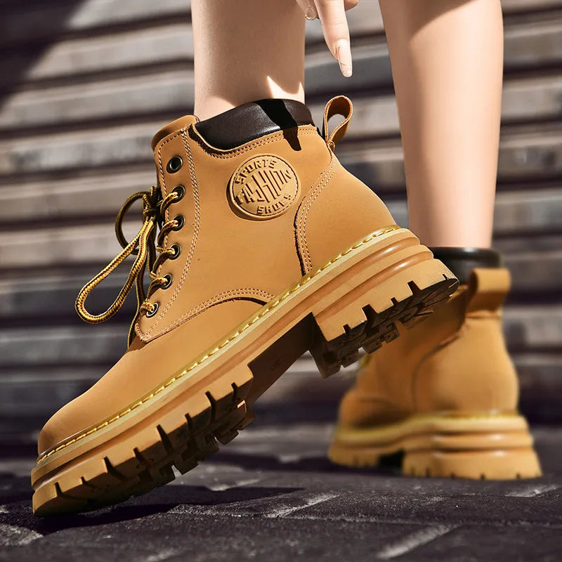 NEWYORKLISTED: Tan work boots with brand logo on a blurred outdoor background