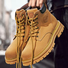 NEWYORKLISTED: Tan leather boots with laces held by a person against a blurred background