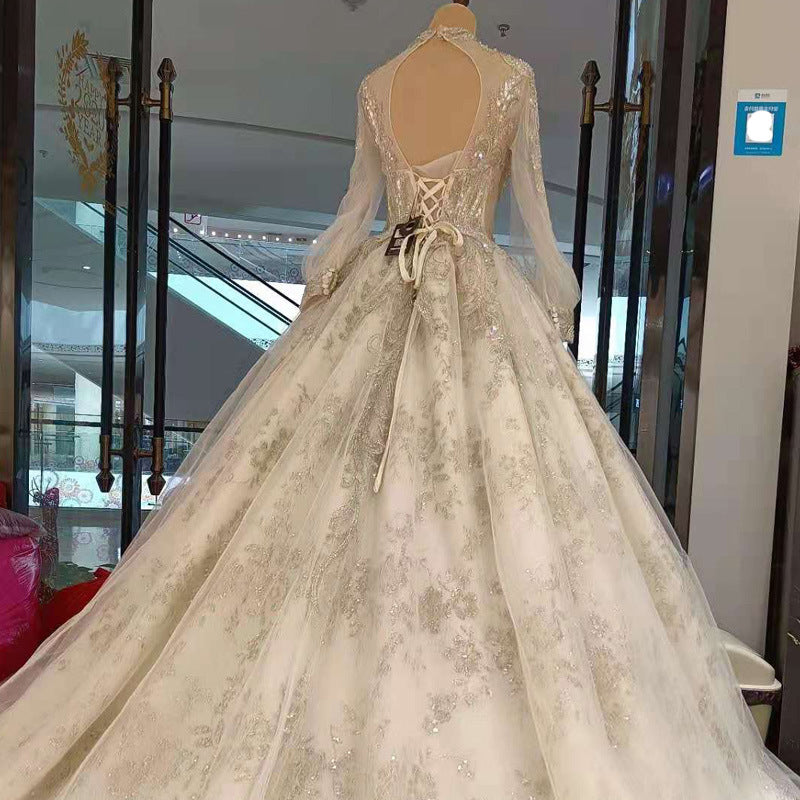 Beige wedding dress with intricate detailing on a mannequin in an indoor setting.