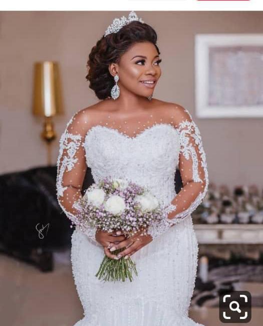 Bride in a white wedding dress holding a bouquet indoors.