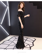 Woman in a black sequin dress standing in a modern interior setting with geometric floor design.