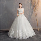 White lace wedding dress on a model against a textured wall.