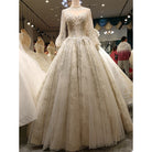 Elegant white wedding dress on a mannequin in a store setting with other dresses and people in the background.