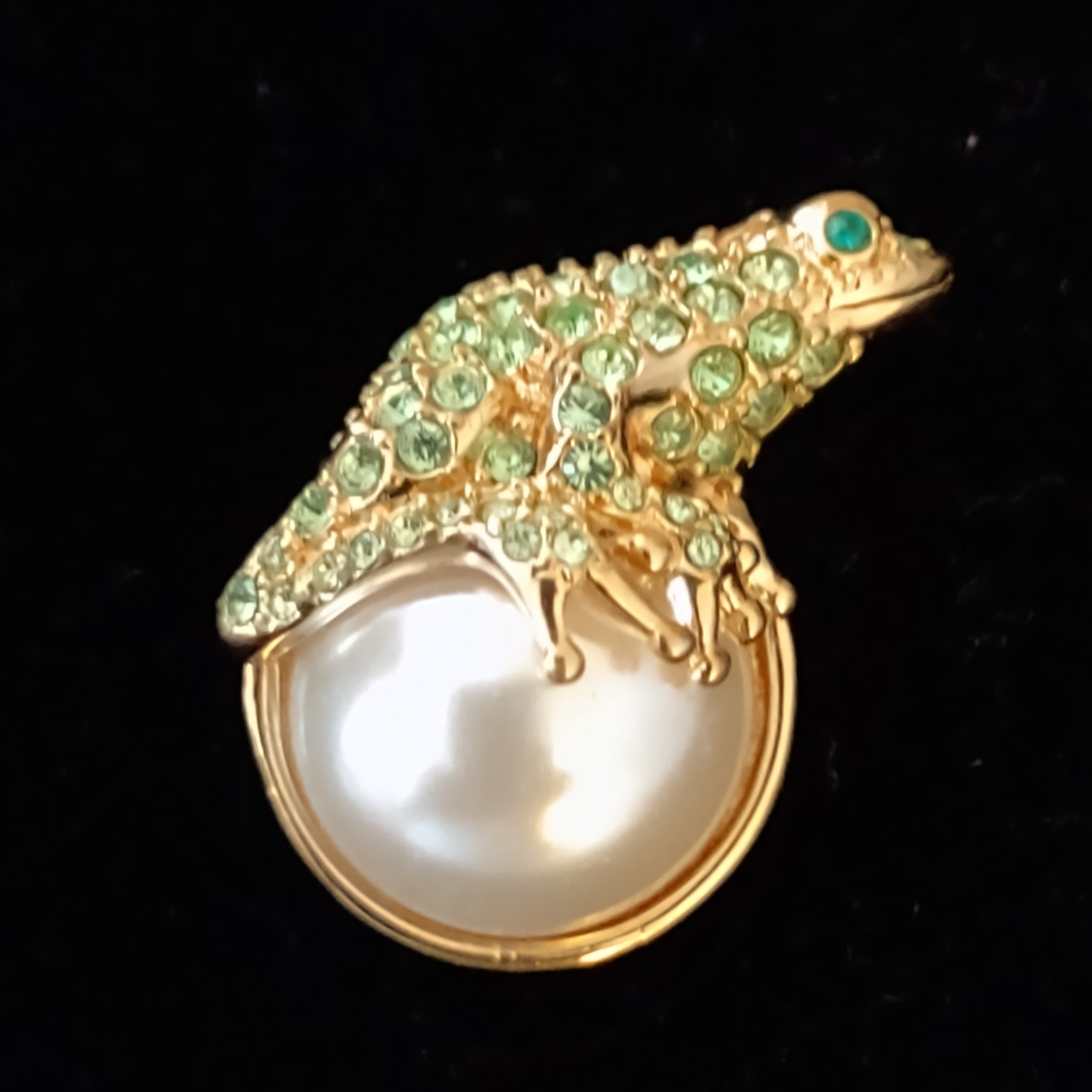 NEWYORKLISTED VINTAGE JEWELRY COLLECTION: Bejeweled frog perched on a large, simulated pearl against a black background