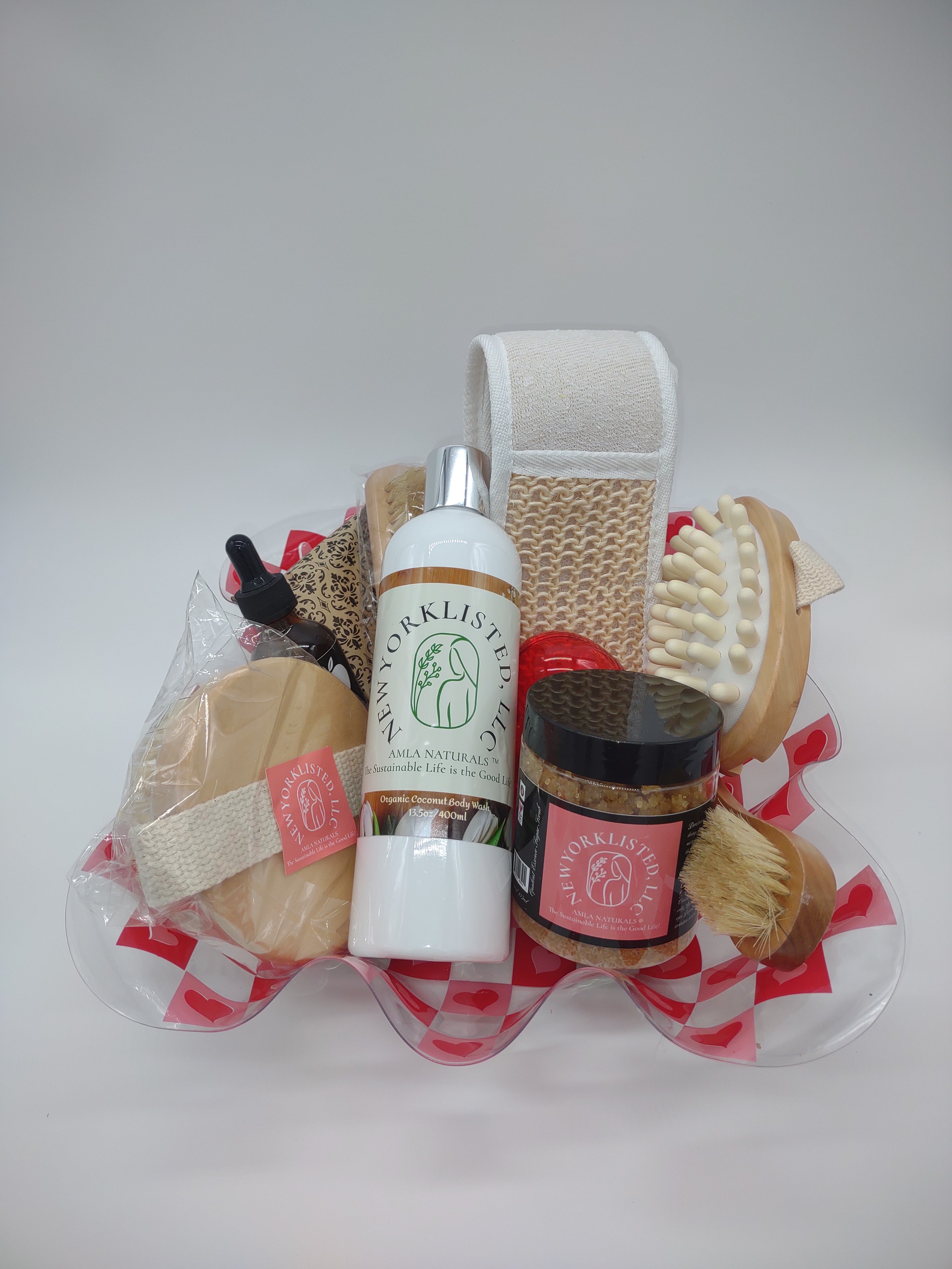NEWYORKLISTED Valentine’s Day Luxury Spa Gift Basket, Set of bath products including a bottle, brush, and loofah on a white background