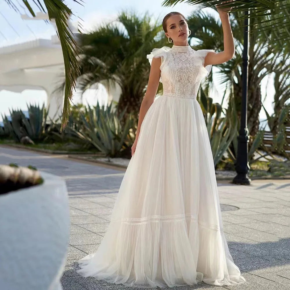 Customizable sleeveless A-line wedding dress with sheer tulle, lace detailing, high neckline, and court train from NEWYORKLISTED Elegant Bride Collection.