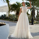 Customizable sleeveless A-line wedding dress with sheer tulle, lace detailing, high neckline, and court train from NEWYORKLISTED Elegant Bride Collection.