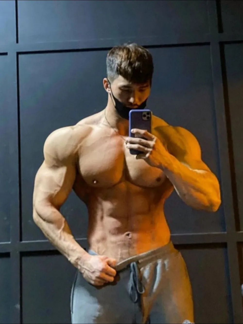 NEWYORKLISTED ATLAS MEN's COLLECTION: Muscular man taking a mirror selfie against a dark wall.