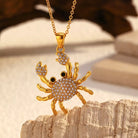NYLD Glamour Collection by NEWYORKLISTED: Gold crab-shaped pendant necklace on a wooden surface