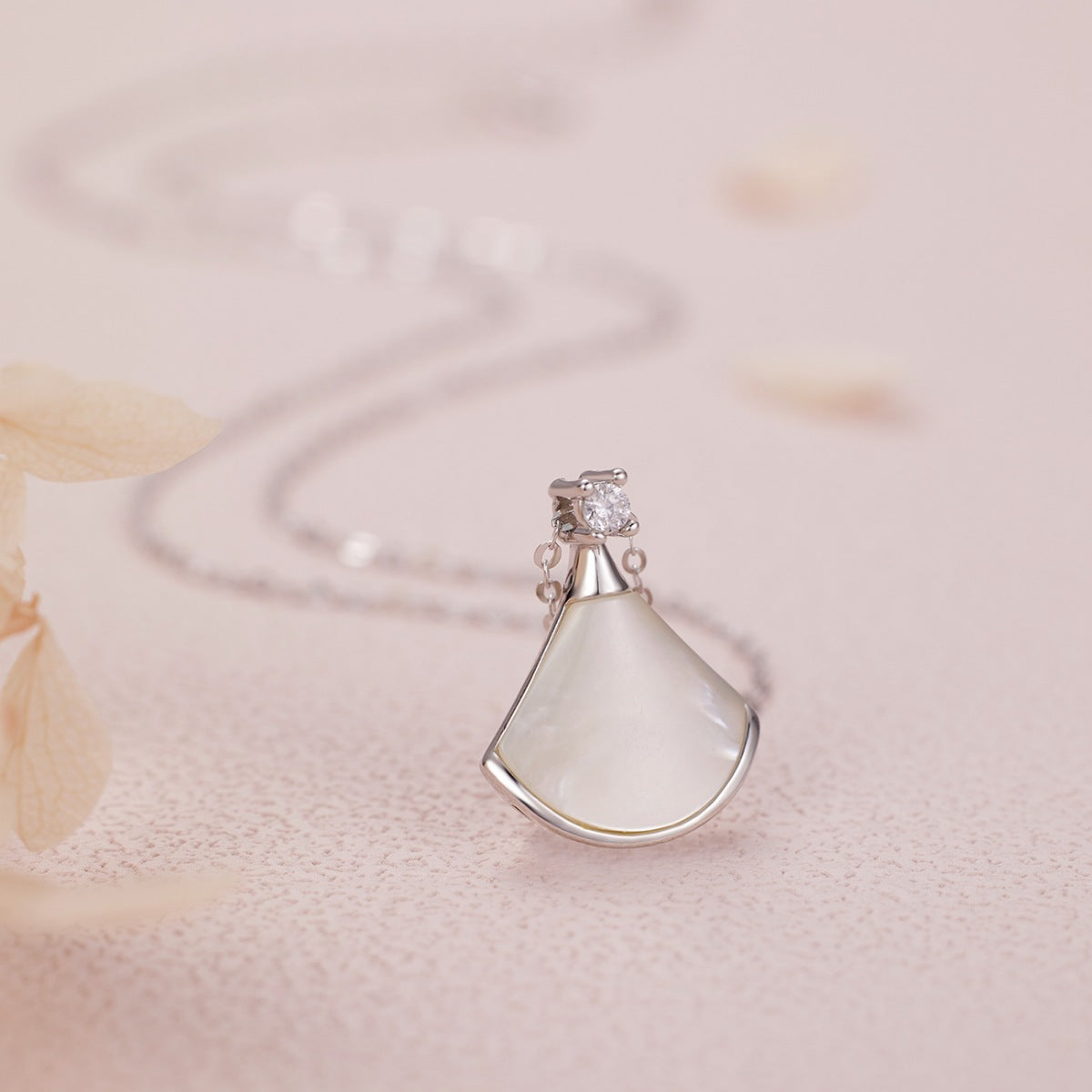 NYLD Glamour By NEWYORKLISTED: Silver pendant with a teardrop-shaped white stone on a soft pink background