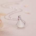 NYLD Glamour By NEWYORKLISTED: Silver pendant with a teardrop-shaped white stone on a soft pink background