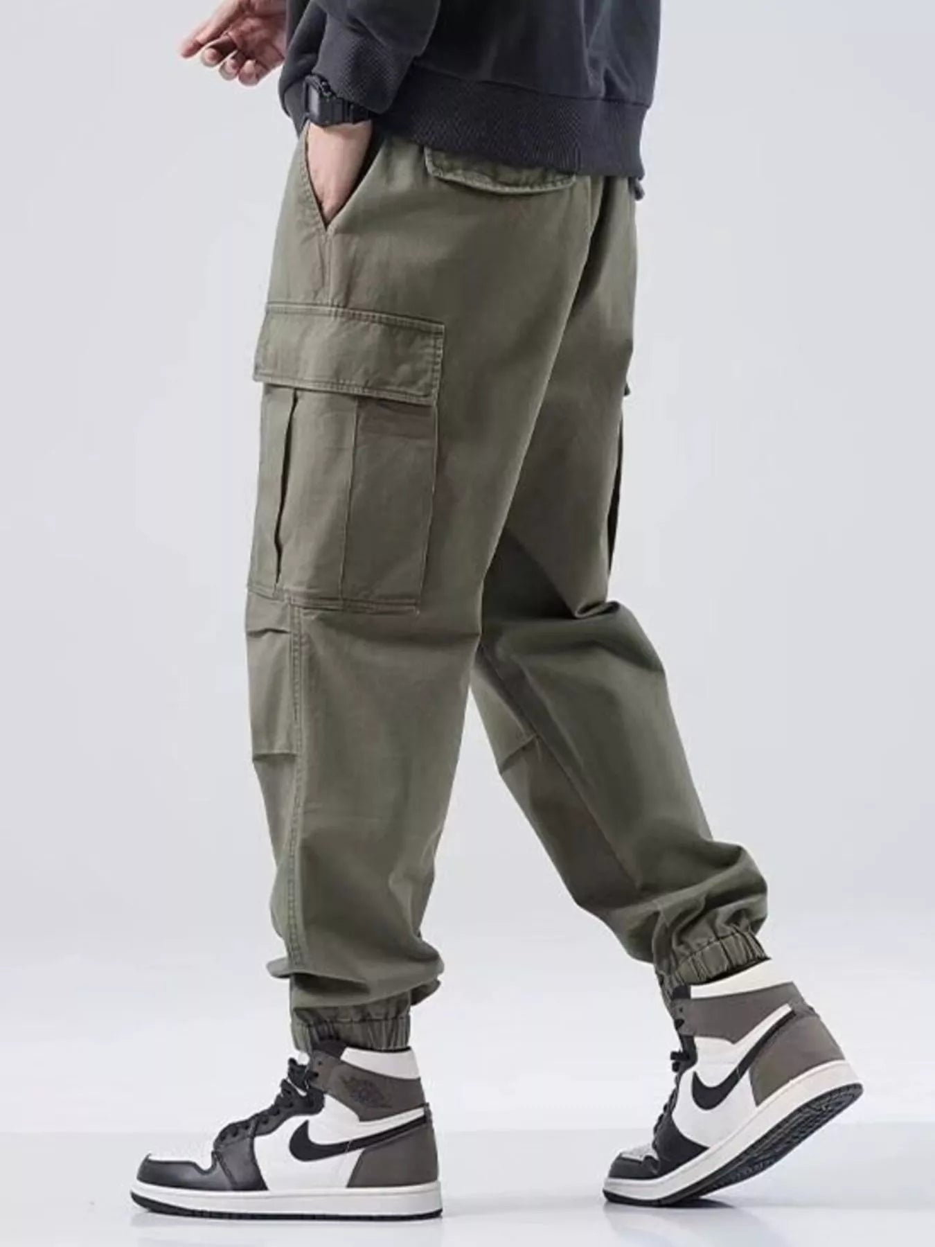 Person wearing olive green cargo pants with a plain background